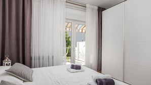 Una habitación de hotel moderna con una cama grande, cortinas blancas y vistas al exterior.