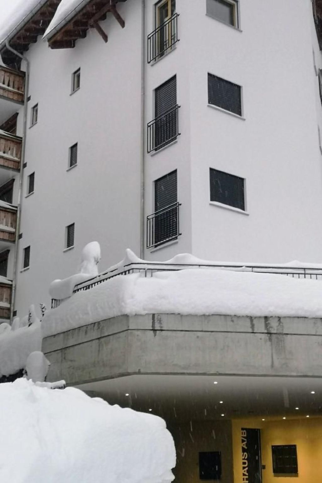 Ein mehrstöckiges Gebäude mit Balkonen und einem mit Schnee bedeckten Dach.