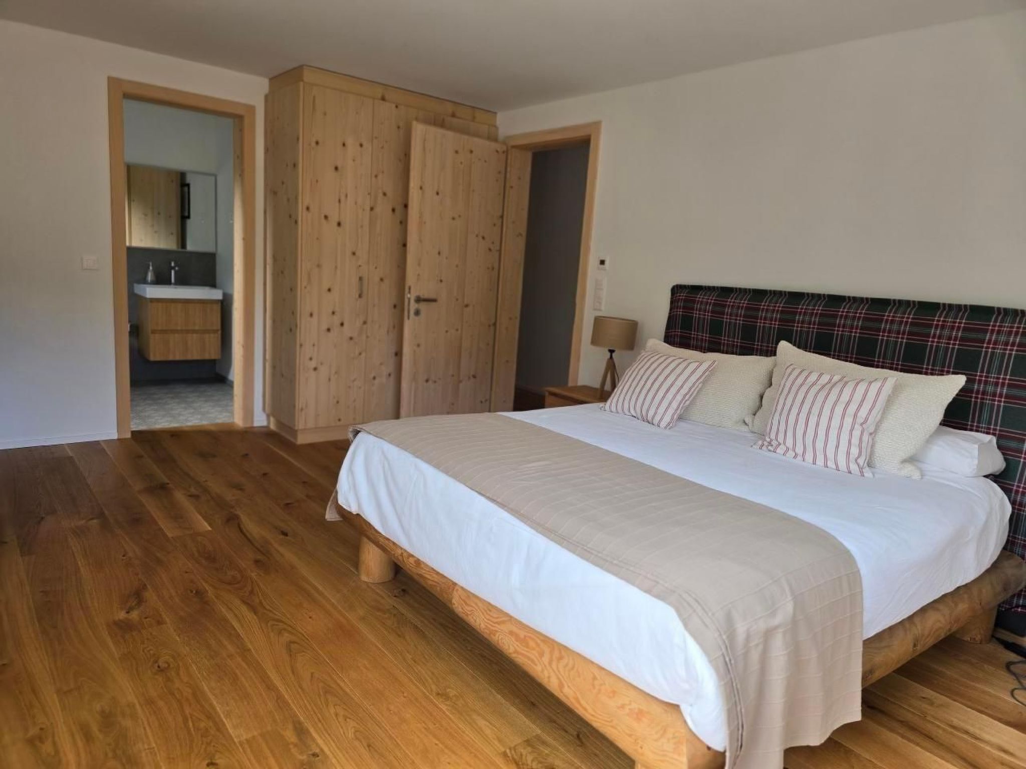 Une chambre à coucher avec un lit en bois, une tête de lit à carreaux et une armoire en bois.