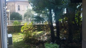 Une cour avec un palmier, une plante en pot et un bâtiment en arrière-plan.