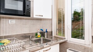 Une cuisine équipée d’un four à micro-ondes, d’un évier et d’une fenêtre.