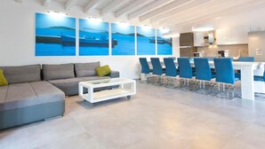 A modern living room with a grey sofa, a white coffee table, and a dining area with blue chairs. - Wellness und Spa Villa Stella, in der Nähe von Stränden - Meer by Interhome (Bokordici)