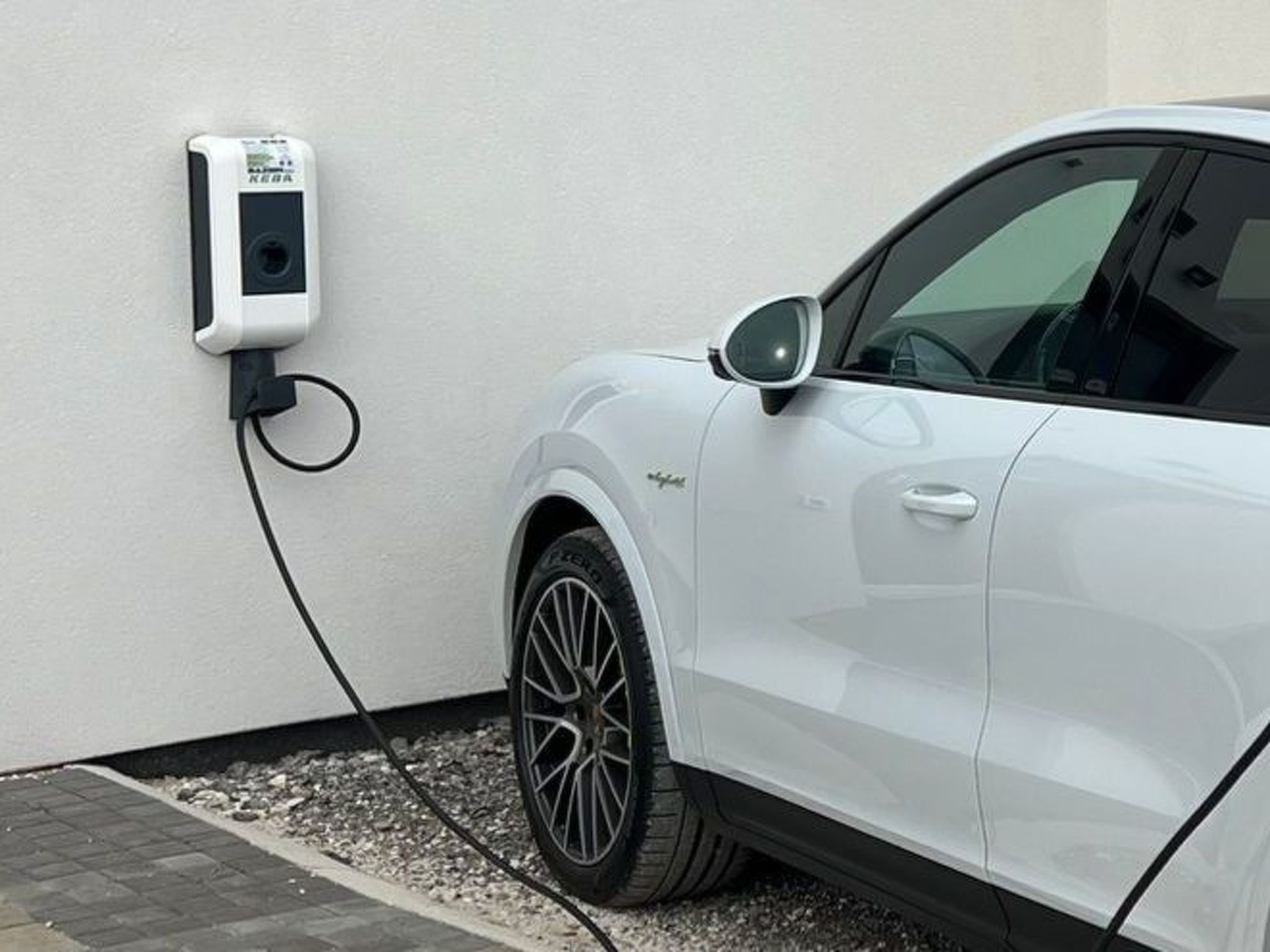 En hvid SUV parkeret ved en ladestation.