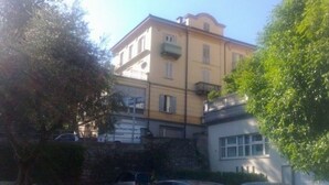 Un edificio a più piani con balconi, auto parcheggiate e aree verdi.