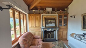 A cozy living room with a fireplace, wooden cabinets, and a sofa. - Executive mit 6 Schlafzimmern und 2 Bädern by Interhome (Lugano)