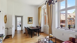 A room with a dining table, chairs, a sofa, a glass coffee table, and a window with curtains. - Gründerzeitvilla by Interhome (Potsdam)