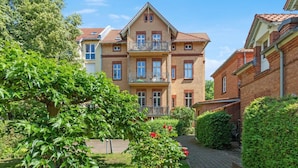 A two-story building with a balcony, surrounded by lush greenery and a paved pathway. - Gründerzeitvilla by Interhome (Potsdam)