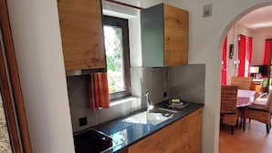 Uma cozinha compacta com armários de madeira, bancada preta e uma janela.