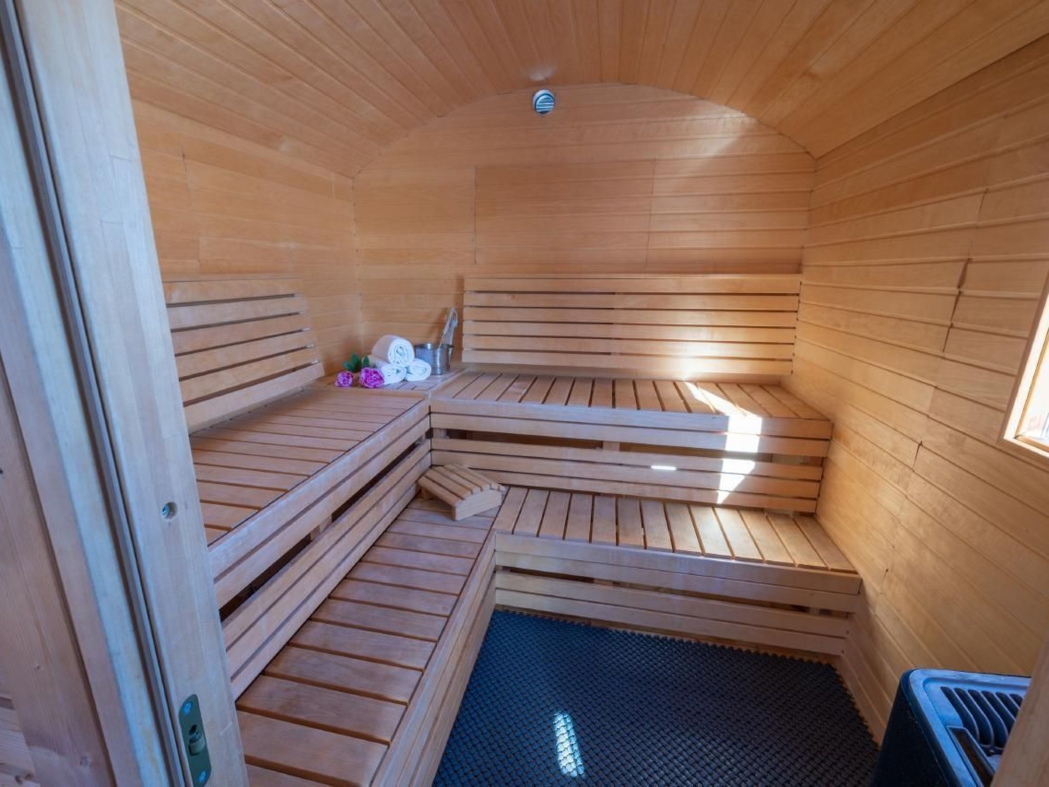 A sauna with wooden benches and a small table with towels and a bucket.