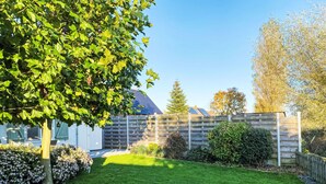 A well-maintained garden with a lawn, a tree, and a wooden fence. - Windekind mit Blick auf die Felder by Interhome (De Panne)
