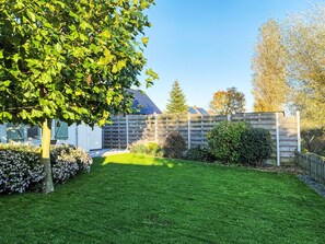 Ein gepflegter Garten mit Rasen, einem Baum und einem Holzzaun.