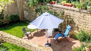 A patio with a table and chairs, a blue umbrella, and potted plants. - Historisches Gourdon by Interhome (Gourdon)