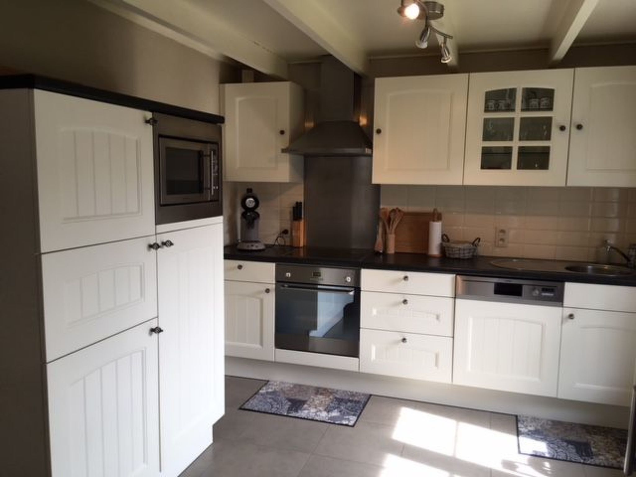 A kitchen with white cabinets, a microwave, oven, and a sink.