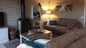 Ett mysigt vardagsrum med en stenmur, en öppen spis, en soffa och ett soffbord.