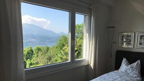 Ein Schlafzimmer mit einem Bett, einem Fenster mit Vorhängen und gerahmten Bildern an der Wand.