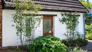 Pieni talo, jossa on tiilikatto, puuovi ja tiilistä rakennettu polku, joka johtaa sisäänkäynnille.