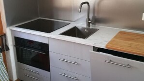 Una cocina moderna con electrodomésticos de acero inoxidable, un lavamanos doble y armarios grises.