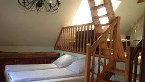 A bedroom with a wooden bed, a wooden staircase, and a chandelier. - in ehemaliger Dorfschule am Dorfrand by Interhome (Bergen)