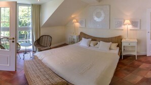 A bedroom with a large bed, a chair, a small table, and a door leading to a balcony. - La Bella by Interhome (Kressbronn)