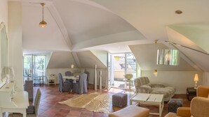 A spacious loft with high ceilings, a dining area with striped chairs, a cozy seating area with a sofa and ottomans, and a large window providing natural light. - La Bella by Interhome (Kressbronn)