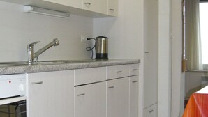 Eine Küche mit weißen Schränken, einer Edelstahl-Spüle und einem Wasserkocher auf der Arbeitsplatte.