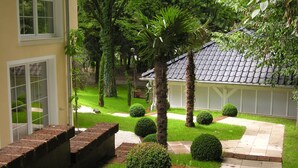 A well-maintained garden with a brick pathway, neatly trimmed bushes, and a palm tree. - Il Giardino by Interhome (Kressbronn)