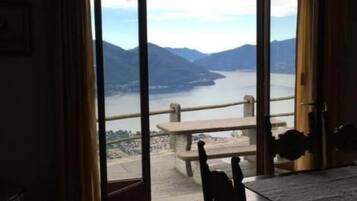 Ein Zimmer mit einer großen Glasschiebetür, die auf einen Balkon mit Blick auf Berge und einen See führt.