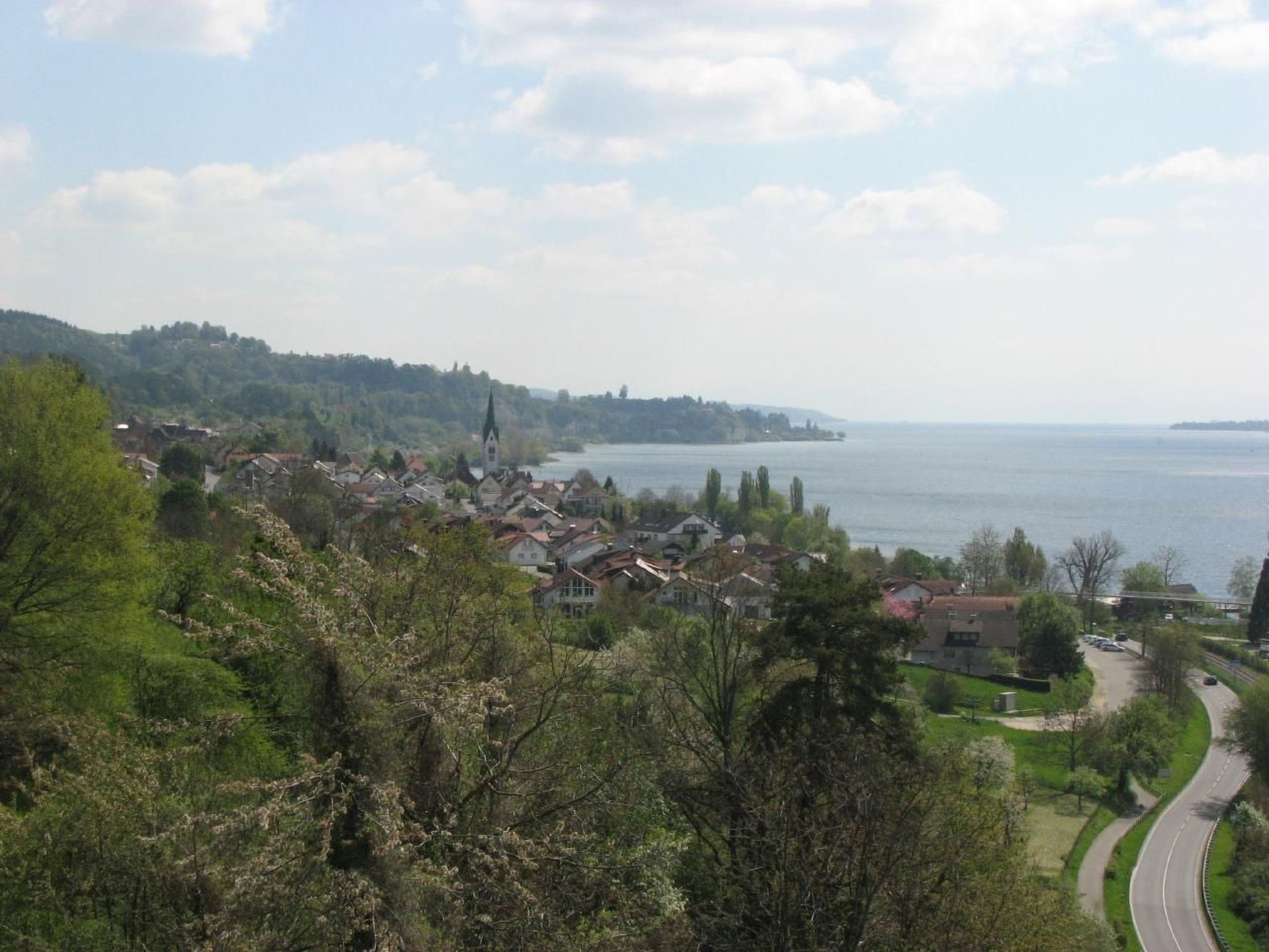 A coastal town with a prominent church, lush greenery, and a winding road.