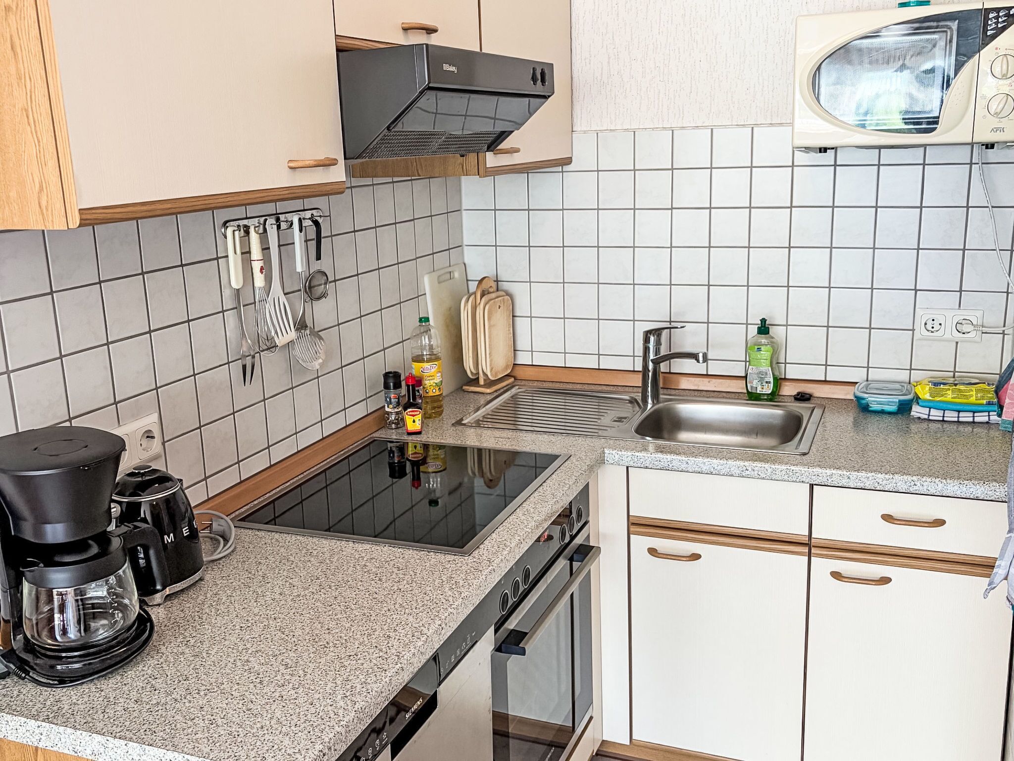 Eine Küche mit eingebautem Backofen, einer Kaffeemaschine und verschiedenen Kochutensilien.