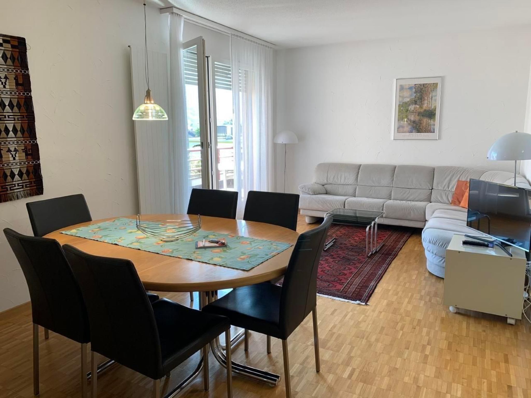 A modern living room with a dining area, featuring a sofa, a coffee table, and a dining table with chairs.