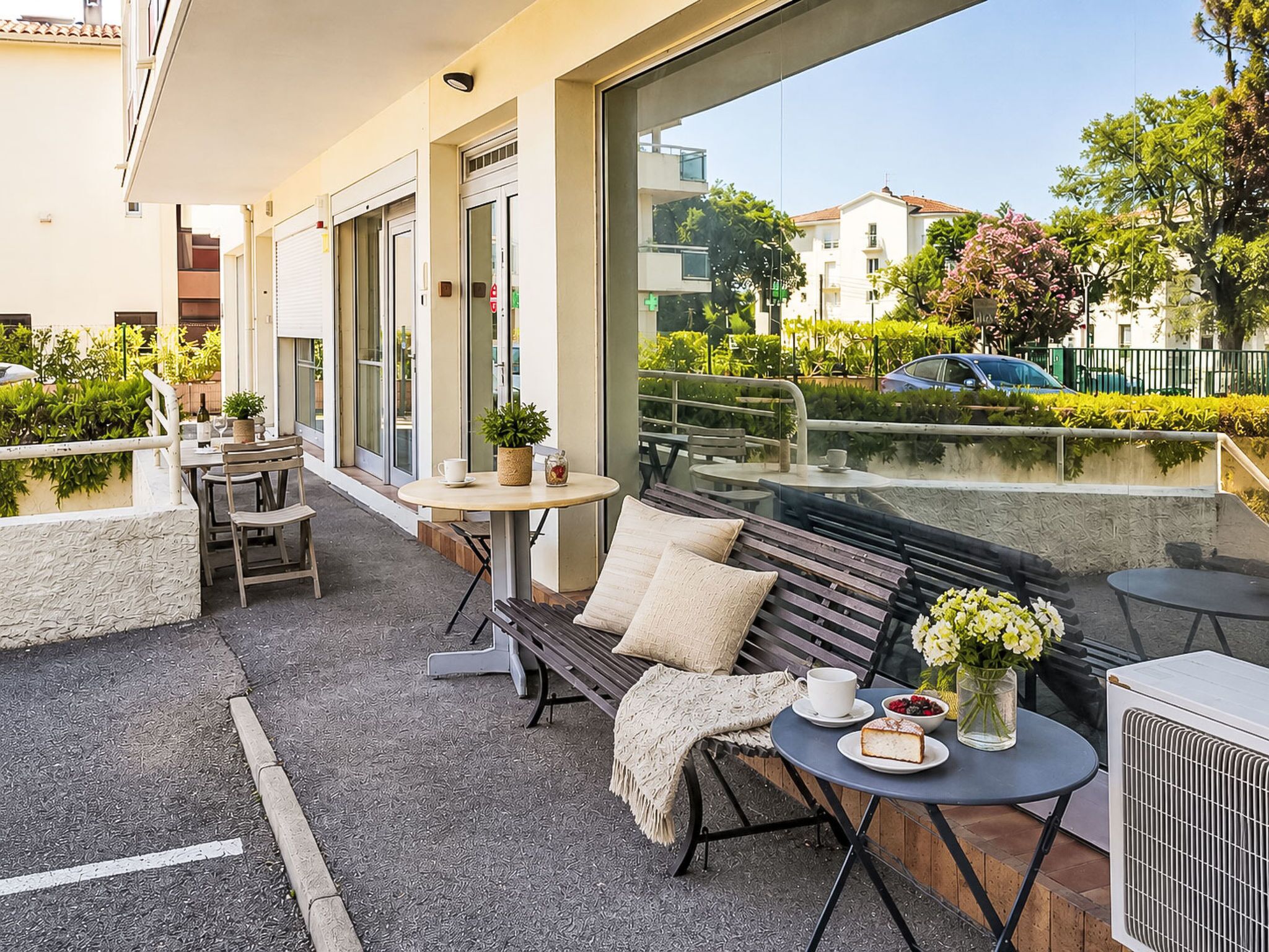 An outdoor seating area with tables, benches, and a view of the street.