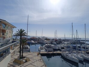Ein Yachthafen mit vertäuten Booten, ein Gebäude mit Balkonen und ein klarer Himmel.