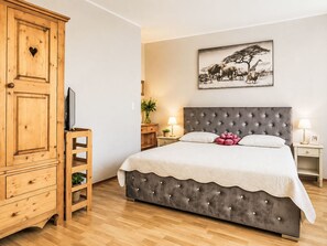 A bedroom with a large bed, a wooden wardrobe, a television, and a framed picture on the wall. - Ferienwohnung Chez-Moi by Interhome (Fréjus)