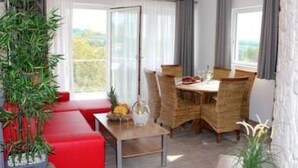Zona pranzo con tavolo e sedie, una ventola a soffitto e vista sull'esterno.