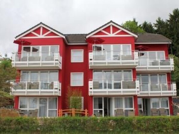 Un edificio rosso a più piani con balconi e ampie finestre.