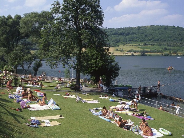 A lakeside park with grassy areas, picnic tables, and a dock.