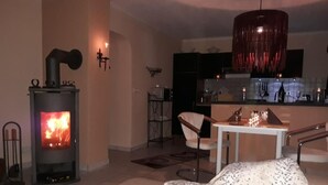 Un accogliente soggiorno con un camino a legna, un'area pranzo con tavolo e sedie, e una cucina sullo sfondo.