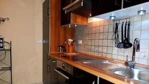 Una cucina moderna con piano di lavoro in legno, lavello in acciaio inossidabile e pensili neri.