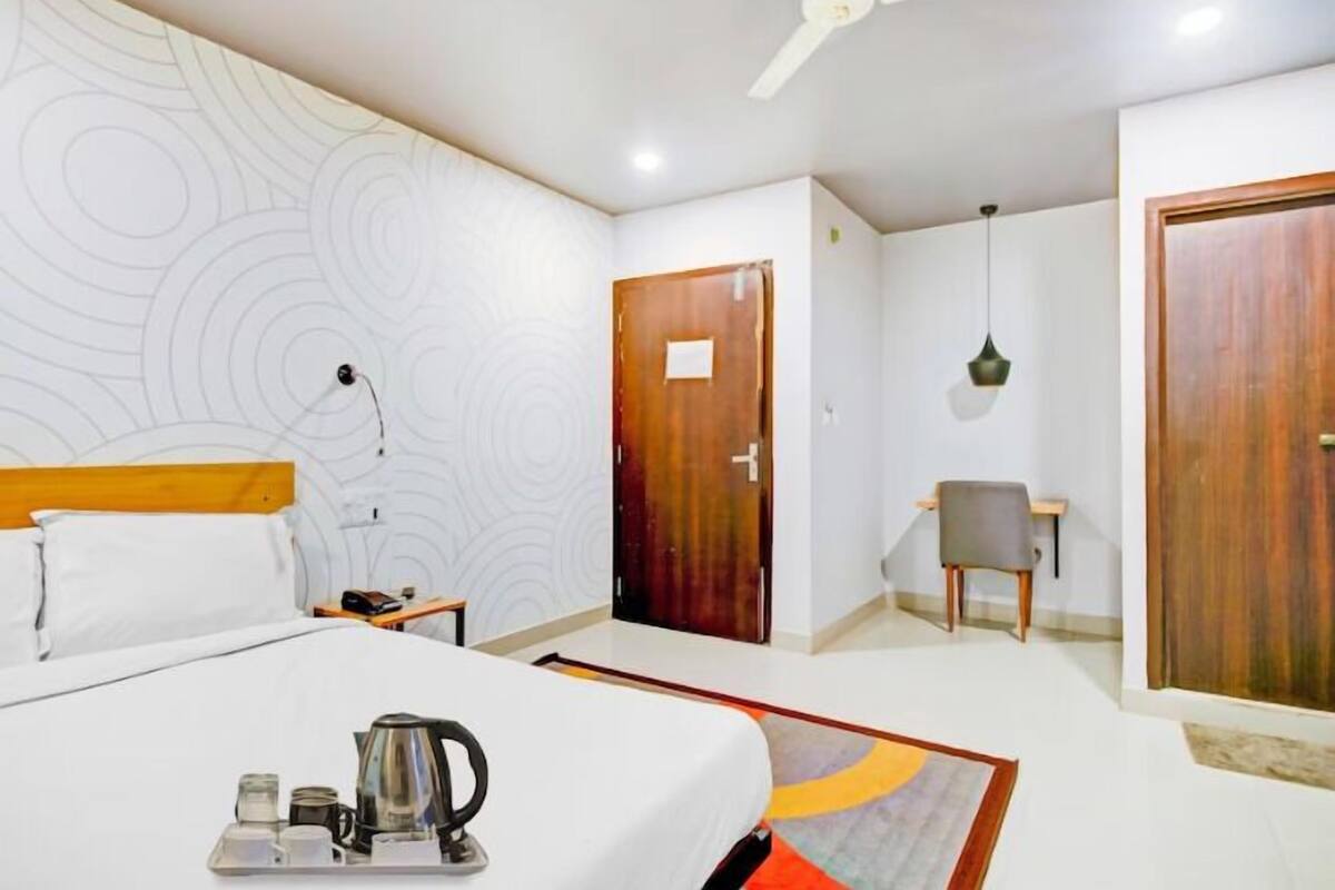 A hotel room with a bed, a desk, a chair, and a wardrobe.