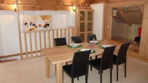 A wooden dining room with a table set for four, black chairs, and a wooden ceiling with exposed beams. - Casa Isabella by Interhome (Peccia)
