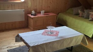 Une pièce confortable avec un lit, une petite table sur laquelle se trouve un verre, et une commode en bois.