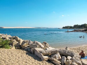 En strand med klart blåt vand, klippeformationer og en sandet kystlinje.
