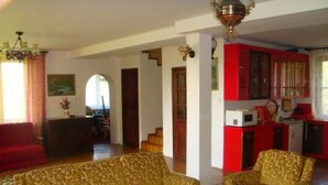 A living room with patterned sofas, a coffee table, a red cabinet, and a kitchen area with a microwave. - in Kaschubei am eigenen See by Interhome (Suleczyno)