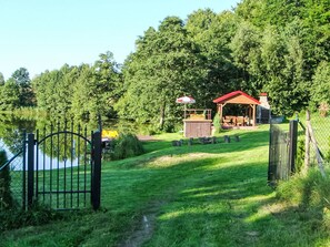 A lakeside property with a wooden deck, a gazebo, and a fenced area.