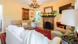 Una sala de estar con chimenea, candelabro y televisor.