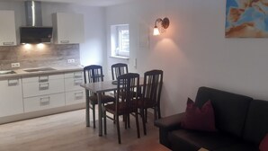 Una cucina moderna con zona pranzo, un divano nero e un quadro appeso al muro.