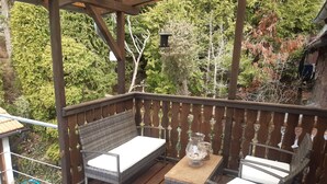 Un patio in legno con mobili in vimini e un vaso di vetro.