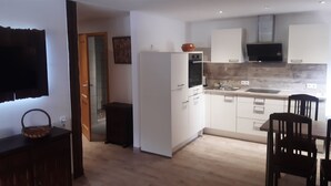 Una cucina moderna con mobili bianchi, un forno a microonde e un lavandino. C'è un'area pranzo con tavolo e sedie.