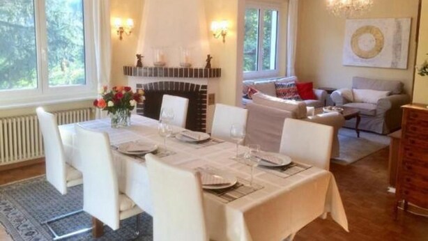 A dining area with a table set for four, a fireplace, and a cozy seating area with a sofa and armchairs. - Casa Elena by Interhome (Locarno Tegna)