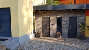A courtyard with cobblestone paving, a stone wall, and two dark-colored doors. - Moderne, niveauvoll eingerichtete Ferienwohnung by Interhome (Carlsfeld)